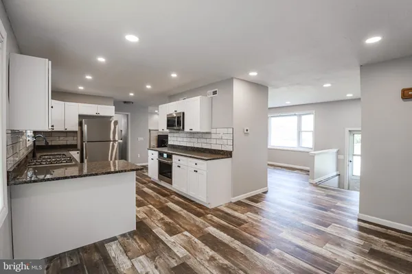 a large kitchen with stainless steel appliances granite countertop a stove a sink and a refrigerator