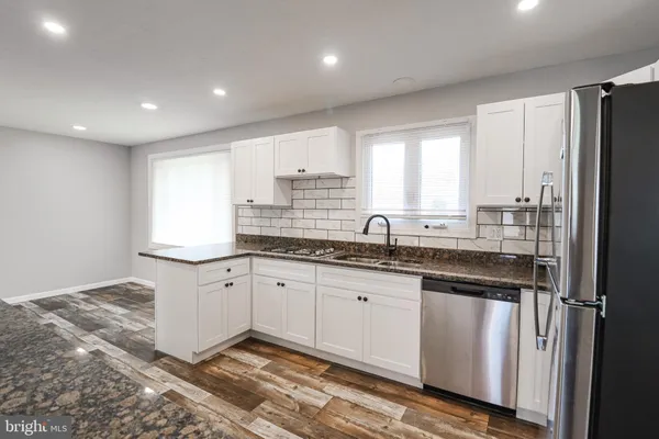 a kitchen with granite countertop a sink stainless steel appliances and cabinets
