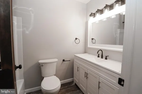 a bathroom with a toilet sink vanity and mirror