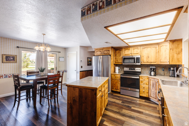 1470 Redwood Tree Street St. George, UT 84790 - Photo 17 of 53 Open-concept kitchen and dining area featuring wood-finish flooring, natural wood cabinetry, stainless steel appliances, and a central island with countertop