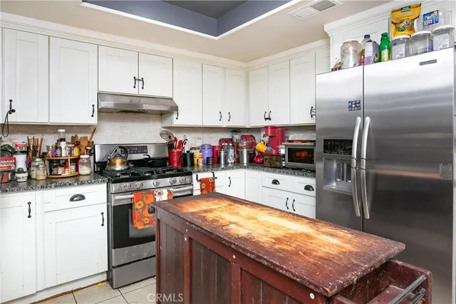 a kitchen with stainless steel appliances granite countertop a refrigerator a stove and white cabinets