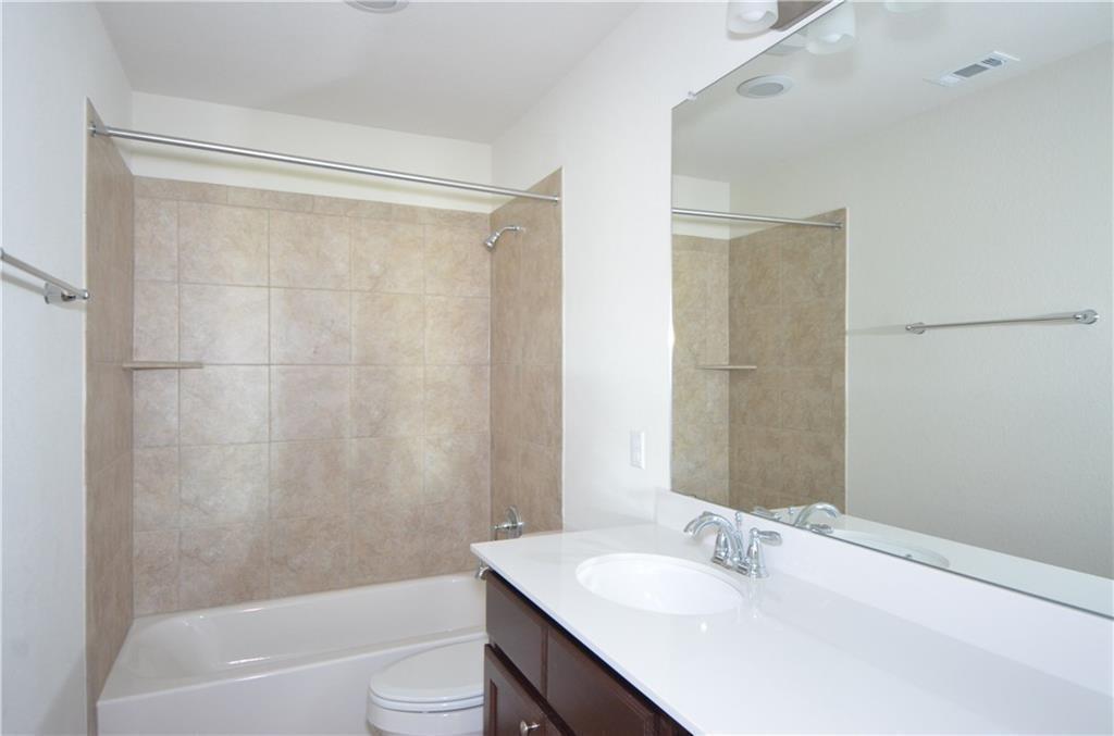 14403 McCoy Loop Austin, TX 78717 - Photo 24 of 29 A well-appointed bathroom features a large vanity with an integrated sink and an adjacent tiled tub-shower combination.