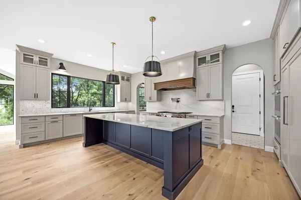 a kitchen with stainless steel appliances granite countertop a stove a sink dishwasher a refrigerator and white cabinets with wooden floor