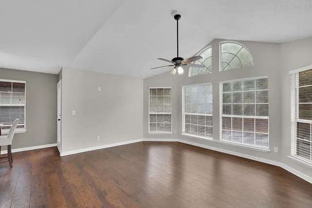 a view of an empty room with a window and wooden floor