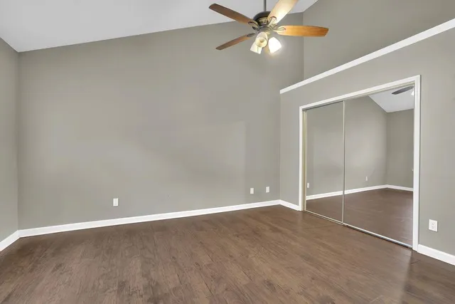 an empty room with wooden floor fan and windows