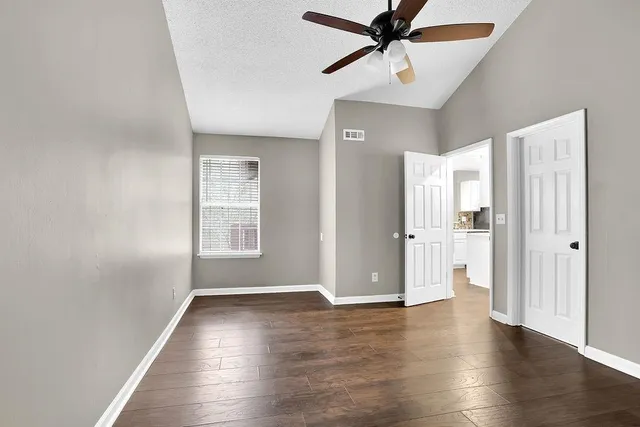 a view of an empty room with window and wooden floor