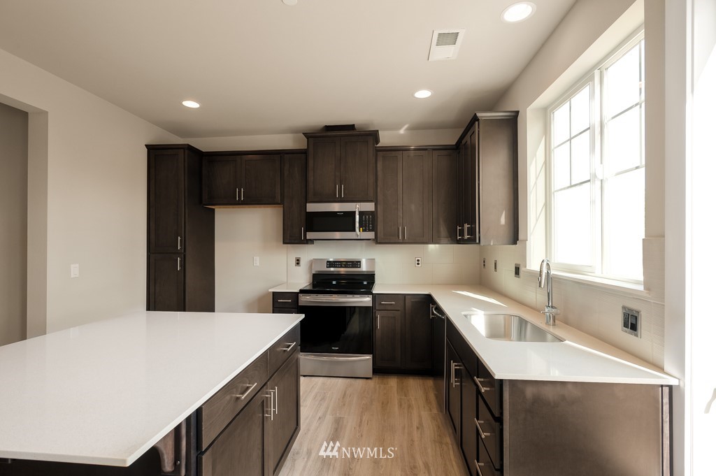 1621 Seattle Hill Road, Unit CC3 Bothell, WA 98012 - Photo 4 of 25 a kitchen with granite countertop a sink a counter top space stainless steel appliances cabinets and a large window