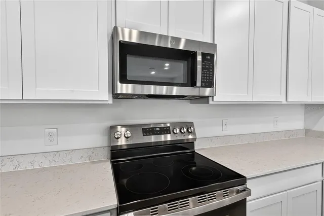 a kitchen with stainless steel appliances granite countertop white cabinets and a stove top oven with granite countertops