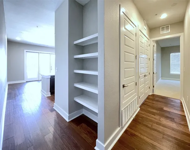 a view of a hallway with wooden floor and closet