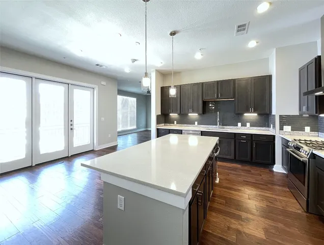 a kitchen with stainless steel appliances granite countertop a sink a stove and a refrigerator