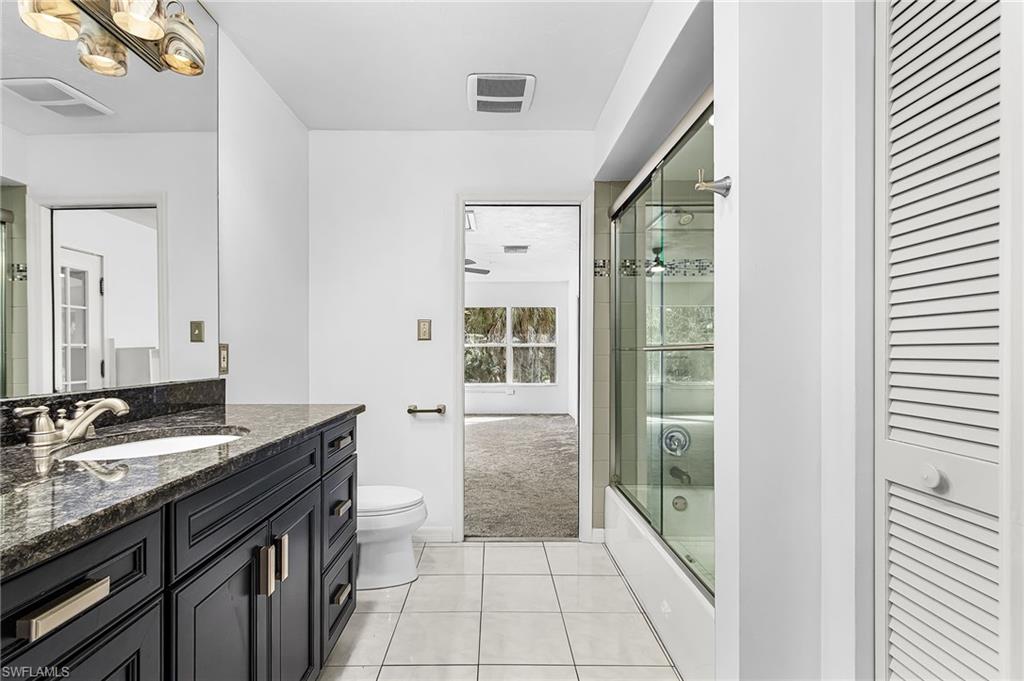 670 27th Street Northwest Naples, FL 34120 - Photo 15 of 39 a bathroom with a granite countertop sink a toilet a mirror and shower