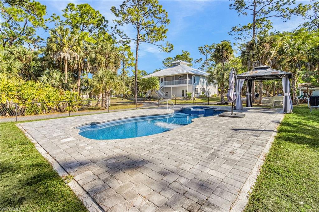 670 27th Street Northwest Naples, FL 34120 - Photo 31 of 39 a view of a swimming pool with lawn chairs under an umbrella