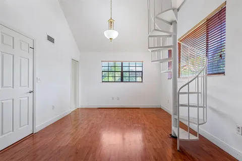 a view of an empty room with wooden floor and cabinets
