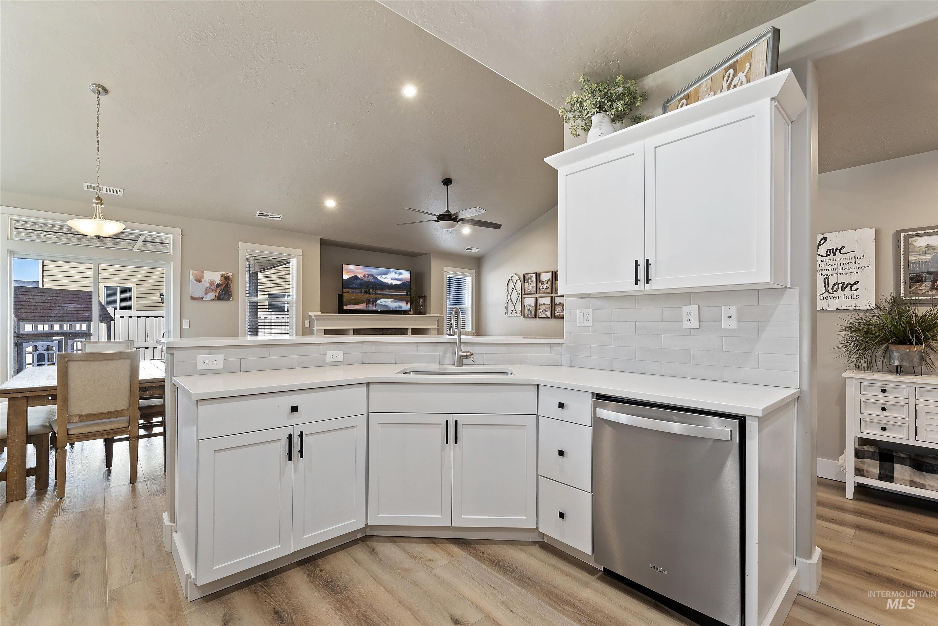 654 Diamond Lake Street Middleton, ID 83644 - Photo 11 of 36 Kitchen with a peninsula, stainless steel dishwasher, lofted ceiling, white cabinetry, and tasteful backsplash