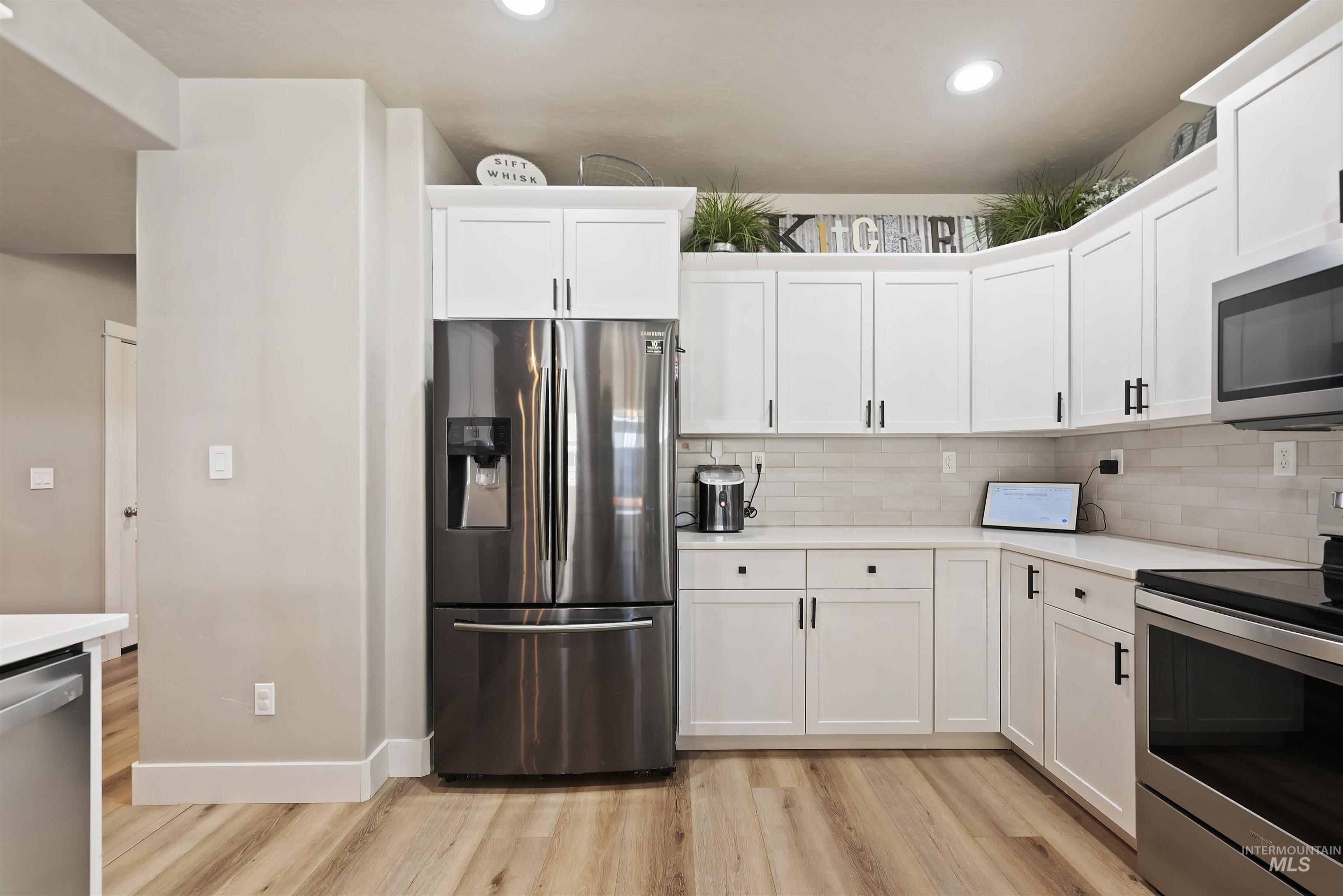 654 Diamond Lake Street Middleton, ID 83644 - Photo 13 of 36 Kitchen featuring stainless steel appliances, white cabinetry, light wood finished floors, recessed lighting, and backsplash