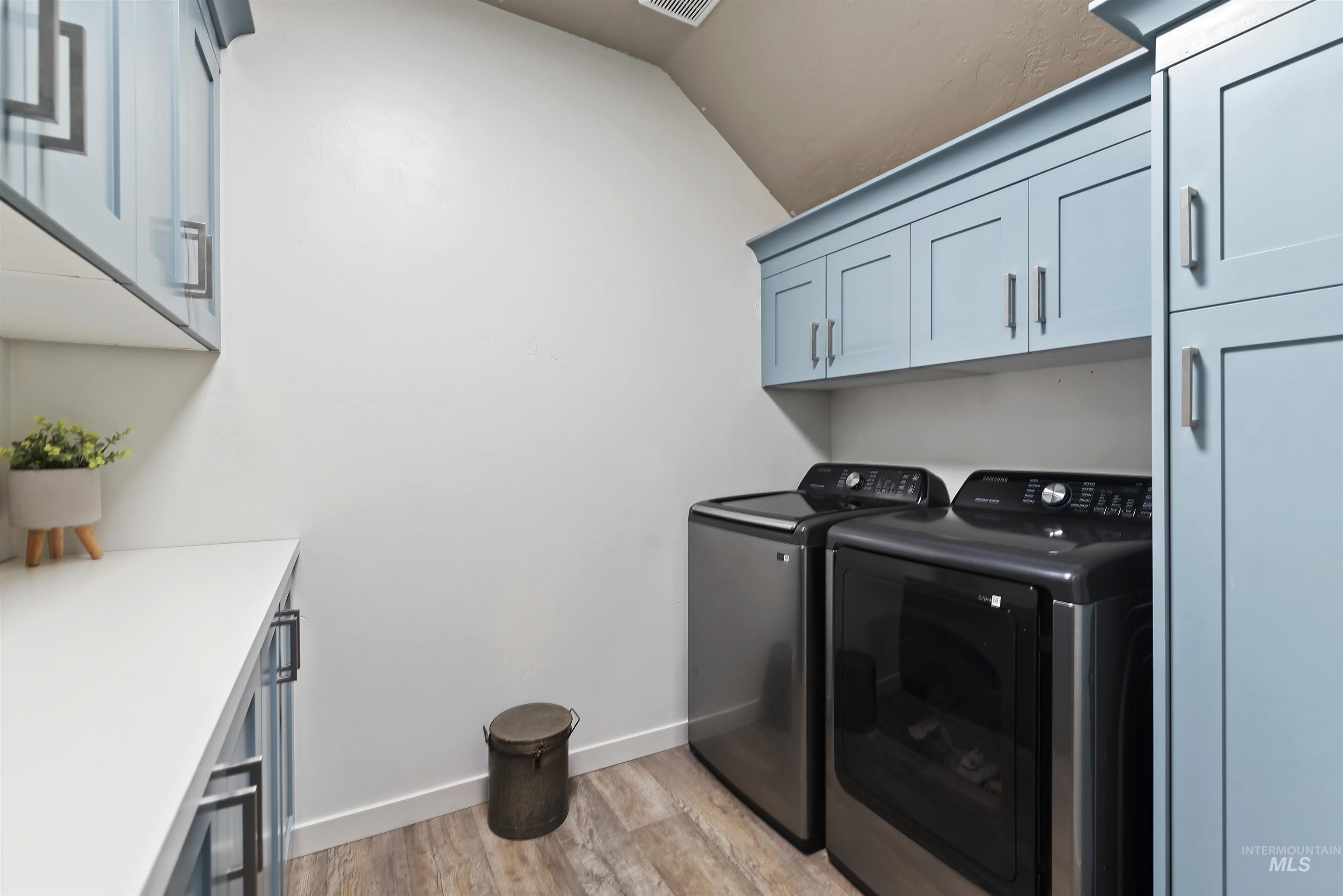 654 Diamond Lake Street Middleton, ID 83644 - Photo 22 of 36 Laundry area featuring light blue cabinets, light wood-style flooring, and washer and clothes dryer