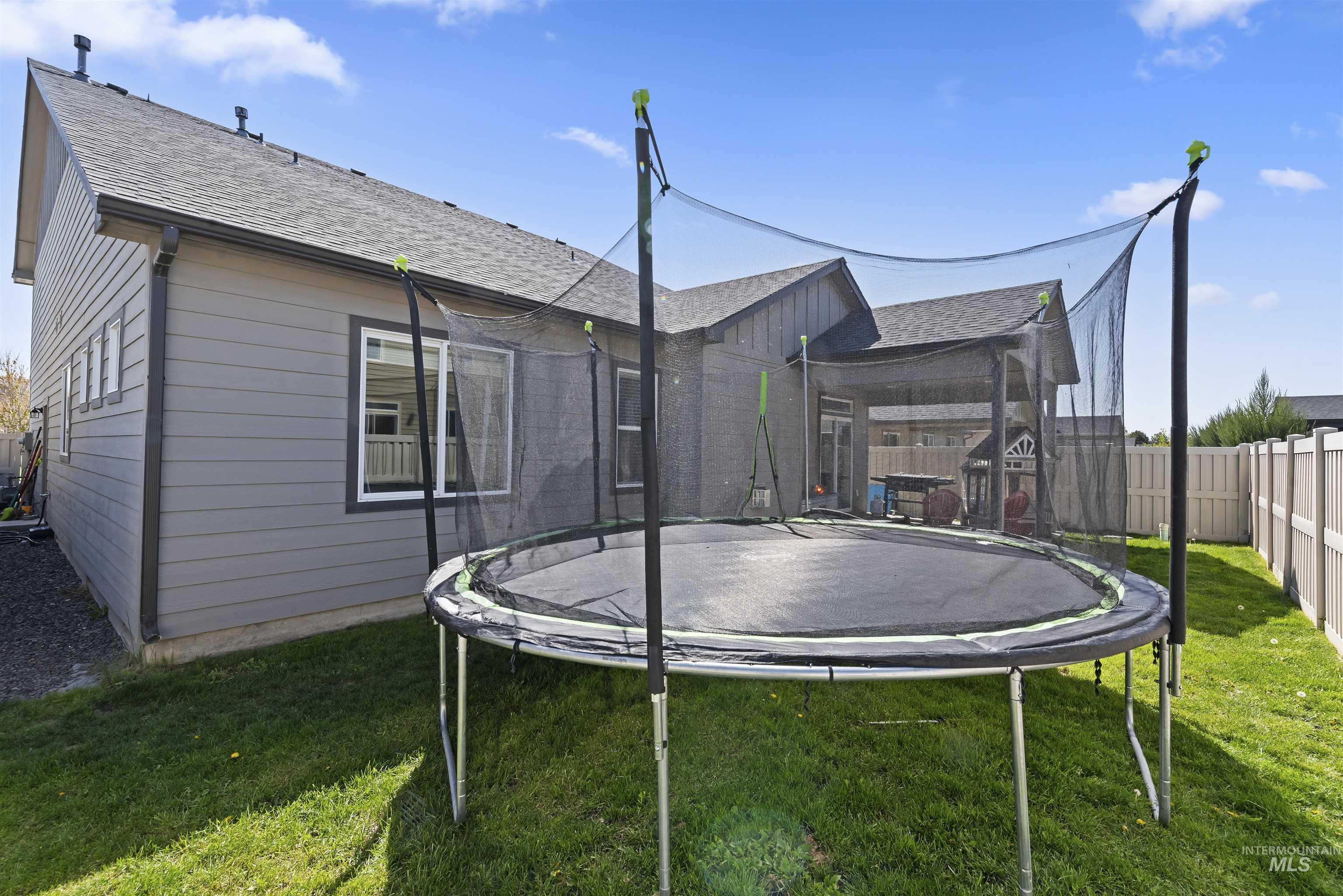 654 Diamond Lake Street Middleton, ID 83644 - Photo 32 of 36 Rear view of property with a trampoline, a shingled roof, a fenced backyard, and covered patio.