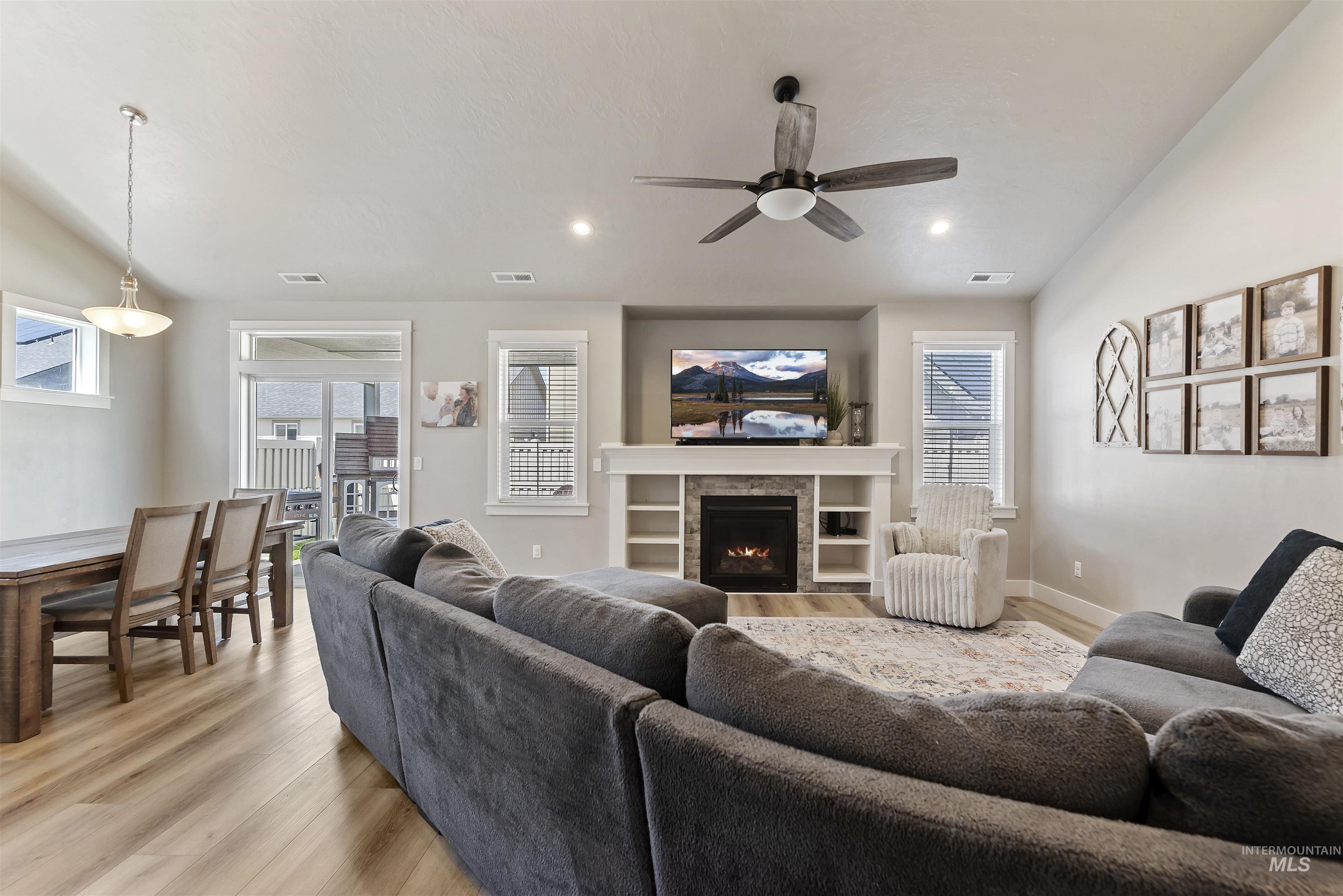 654 Diamond Lake Street Middleton, ID 83644 - Photo 5 of 36 Living room with light wood-type flooring, a ceiling fan, a fireplace, and healthy amount of natural light