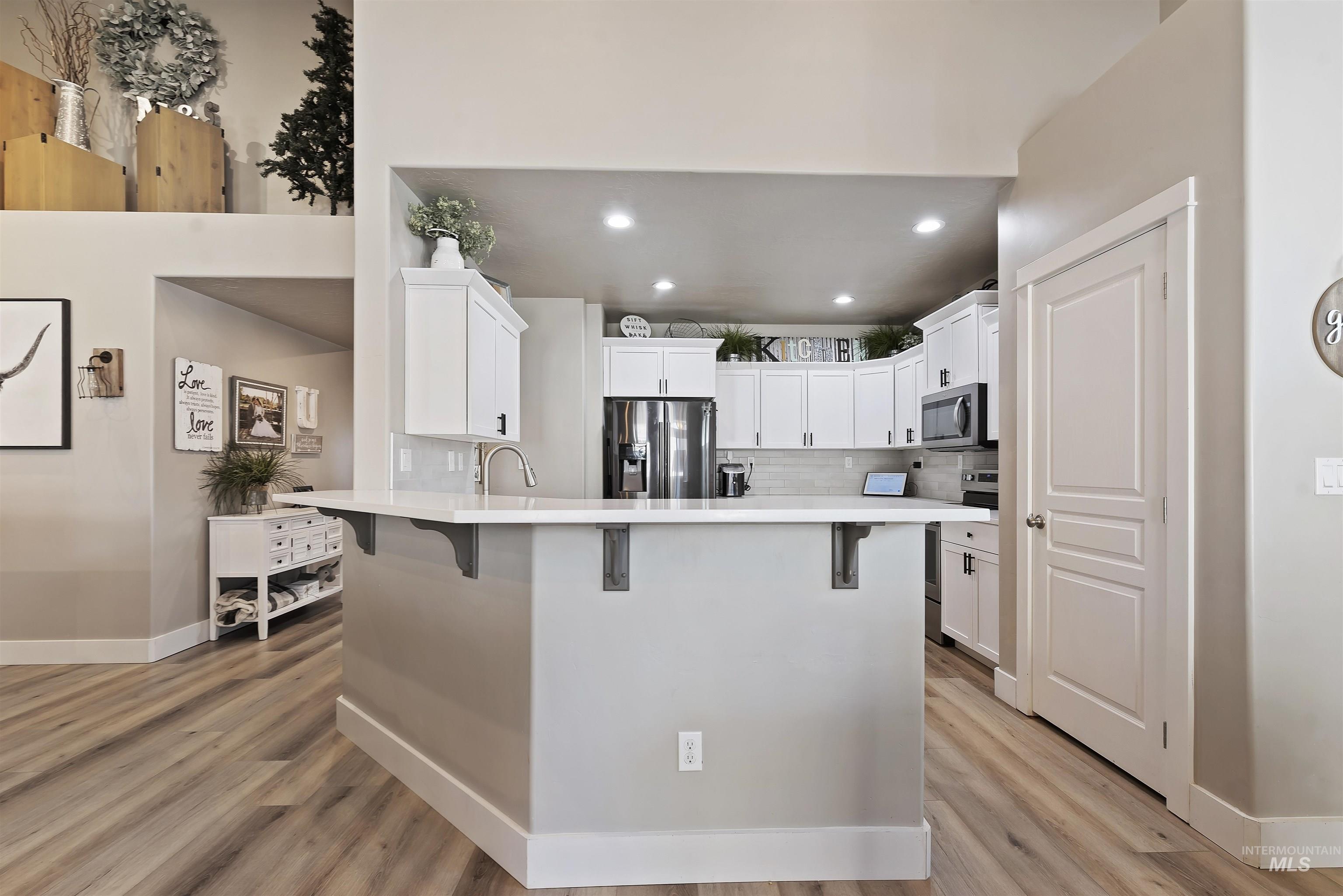 654 Diamond Lake Street Middleton, ID 83644 - Photo 10 of 36 Kitchen with a kitchen breakfast bar, white cabinets, a peninsula, backsplash, and recessed lighting