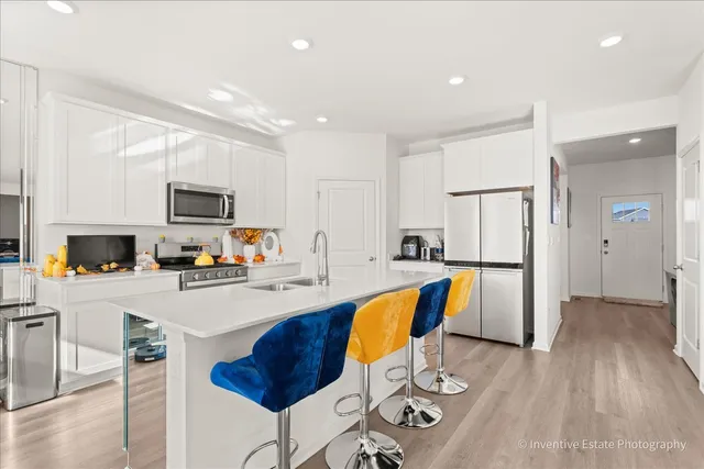 a kitchen with stainless steel appliances granite countertop a refrigerator a stove top oven a sink dishwasher and white cabinets with wooden floor