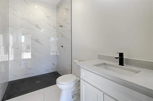 a bathroom with a granite countertop sink a toilet and shower