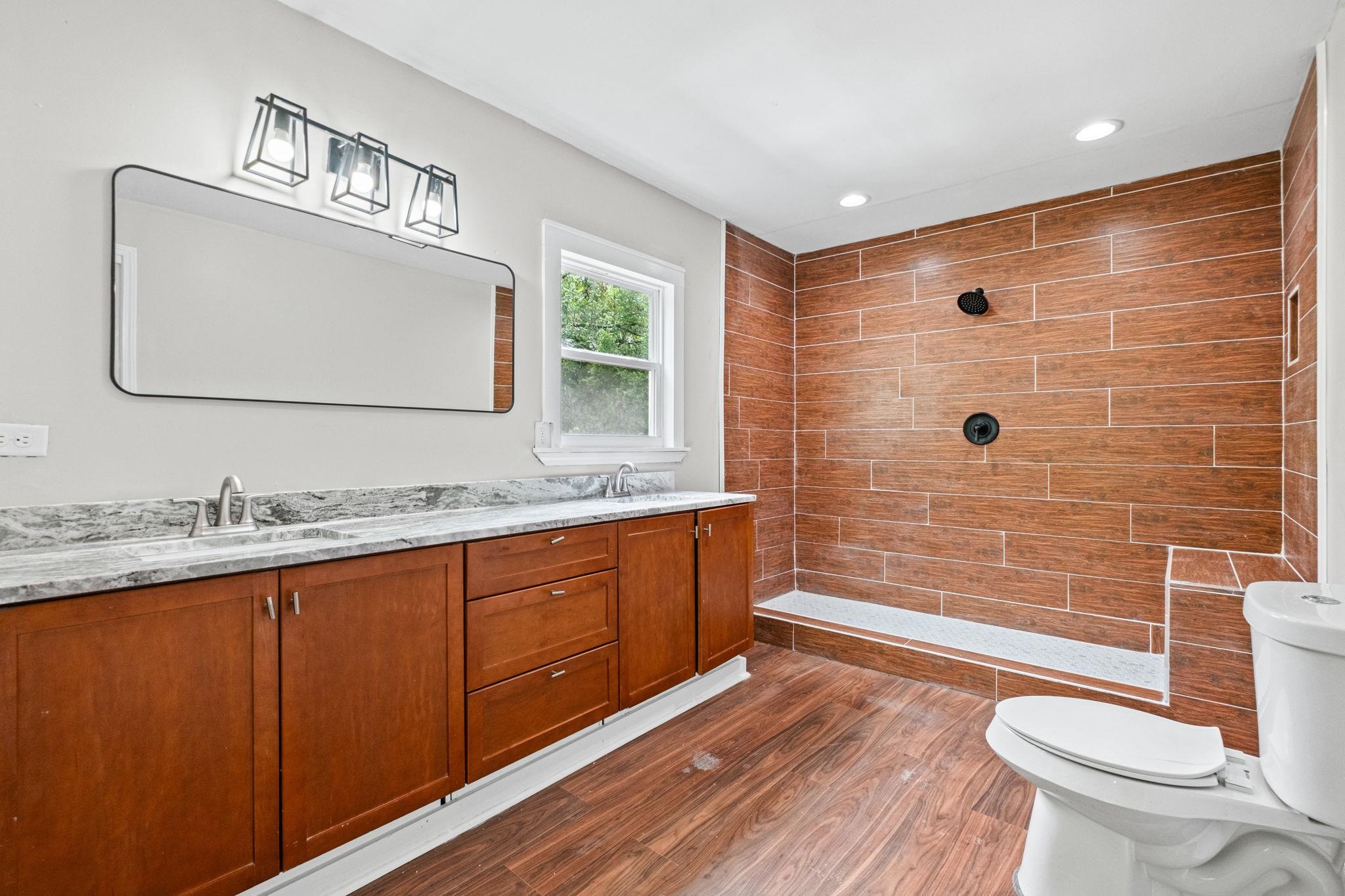 5843 Stewart Road Lakeland, TN 38002 - Photo 18 of 26 Bathroom featuring a wood-finish floor and a wood-look tiled shower with matte black fixtures