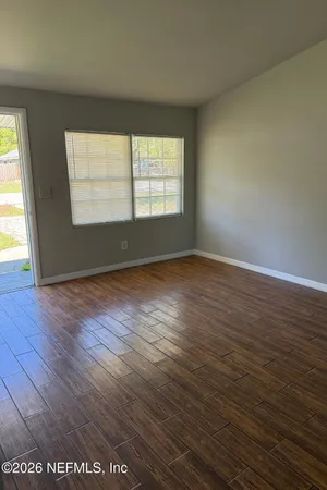an empty room with wooden floor and windows