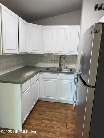 a kitchen with a sink a refrigerator and cabinets