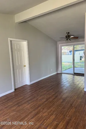 a view of an empty room with wooden floor and a window