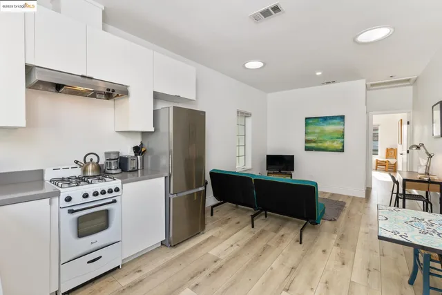 a kitchen with stainless steel appliances a stove a refrigerator and a dining table with wooden floor