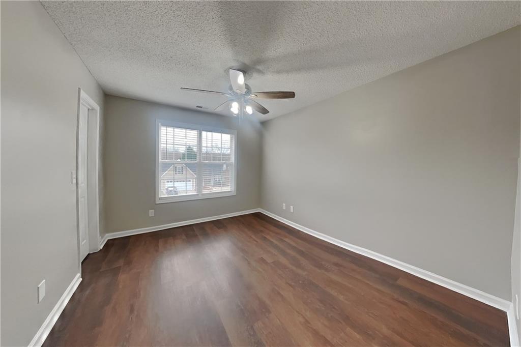 1603 Fort Perry Way Dacula, GA 30019 - Photo 13 of 19 an empty room with wooden floor chandelier fan and windows