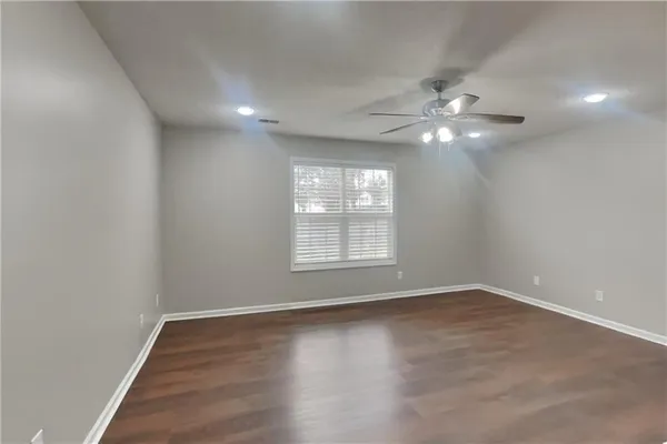 an empty room with chandelier fan and windows
