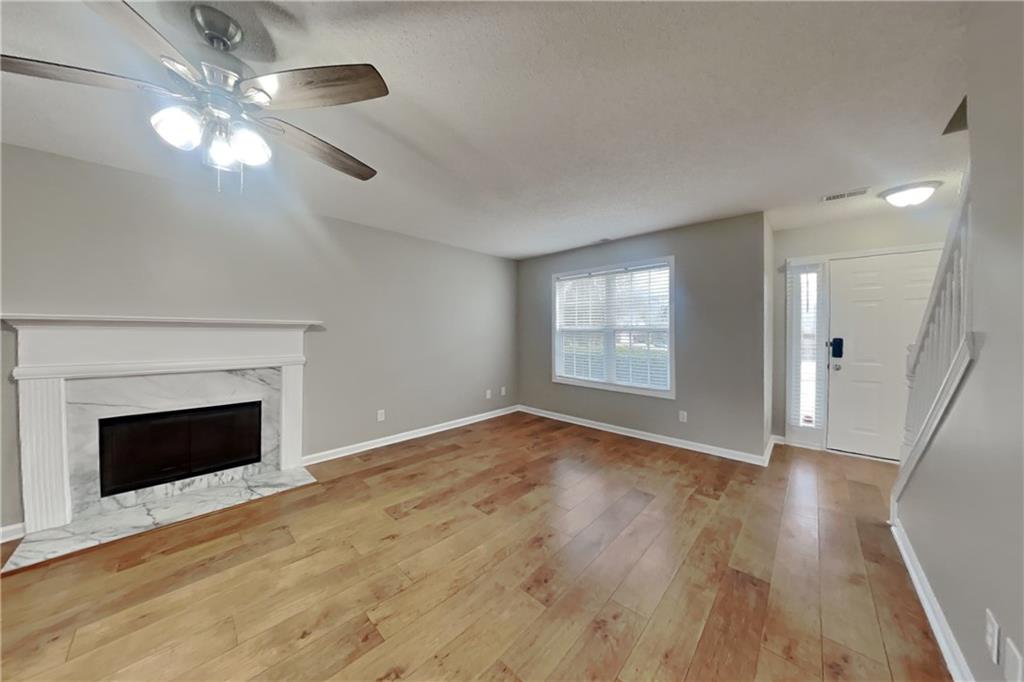1603 Fort Perry Way Dacula, GA 30019 - Photo 3 of 19 an empty room with wooden floor fireplace and windows