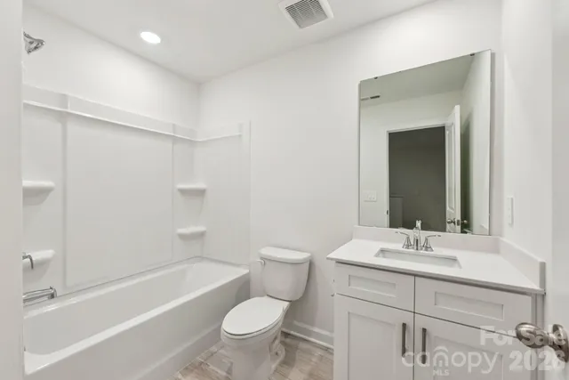 a bathroom with a bathtub shower sink vanity mirror and toilet
