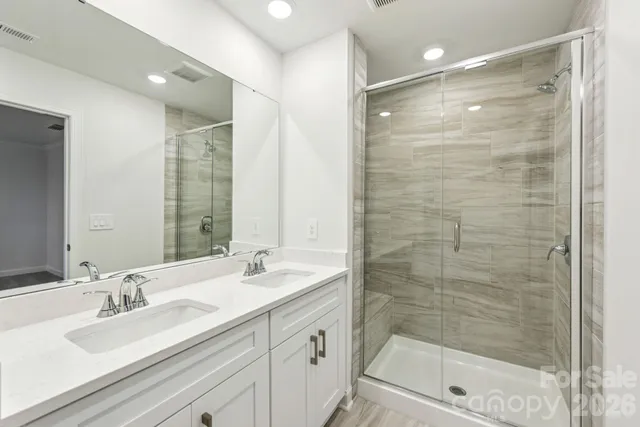 a bathroom with a shower sink vanity granite and mirror