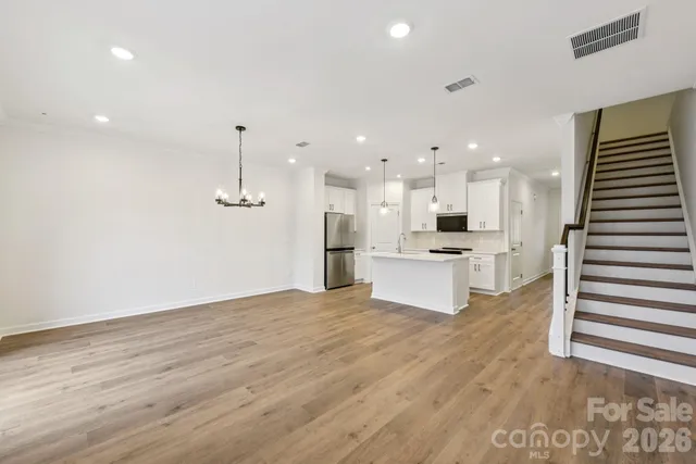 a view of kitchen with kitchen island stainless steel appliances wooden floor cabinets and a window
