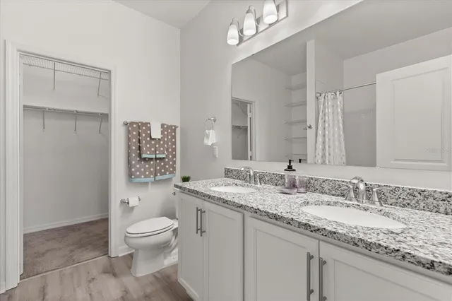 a bathroom with a granite countertop sink a toilet and a mirror