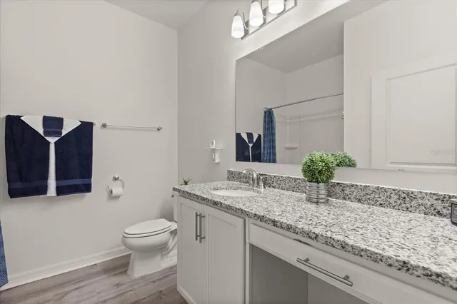 a bathroom with a granite countertop sink and a toilet