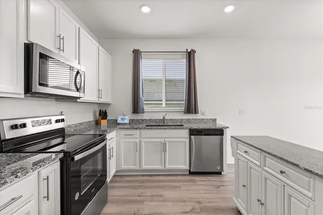 a kitchen with stainless steel appliances granite countertop a stove a sink and a microwave