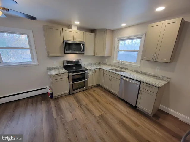 a kitchen with granite countertop wooden floors appliances and sink