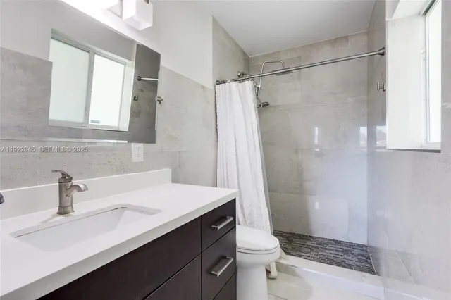 a bathroom with a sink a toilet a mirror and shower