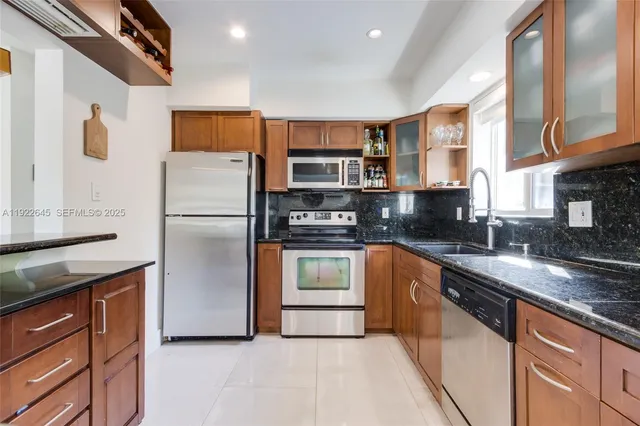 a kitchen with stainless steel appliances granite countertop a refrigerator a stove and a sink