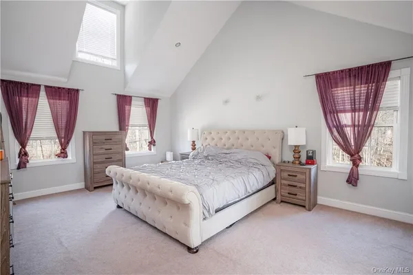 a spacious bedroom with a bed and a dresser next to a window