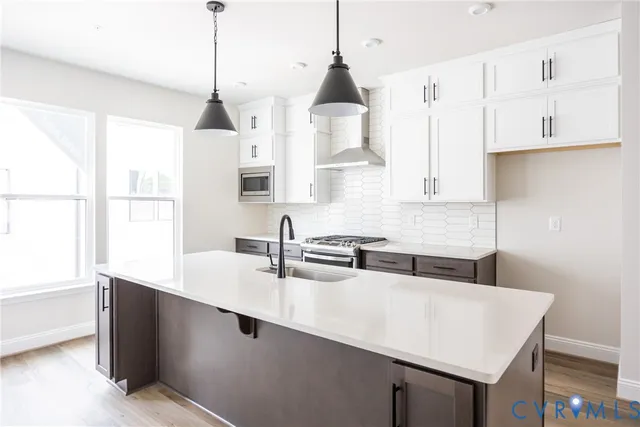 a kitchen with stainless steel appliances a sink a stove and white cabinets