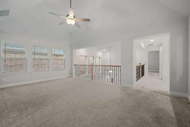 a view of an empty room with a ceiling fan and windows