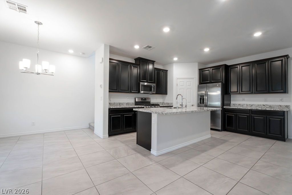 7126 Calvert Cliffs Street North Las Vegas, NV 89084 - Photo 8 of 44 Culinary delights await in this modern kitchen, featuring an island with seating and sophisticated dark cabinetry.