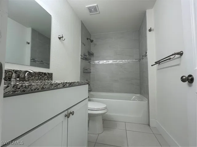 a bathroom with a granite countertop sink a toilet and a mirror