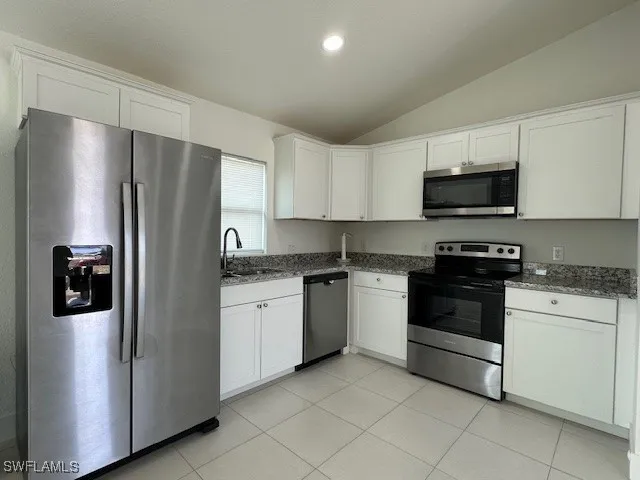 a kitchen with stainless steel appliances granite countertop a refrigerator stove a sink and a microwave oven