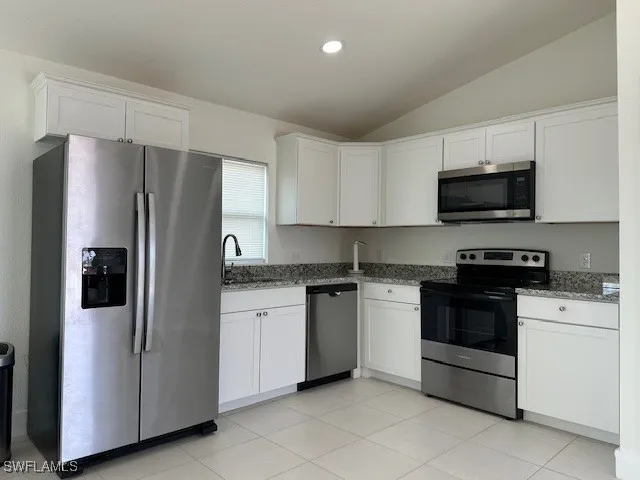 a view of an empty room and a kitchen