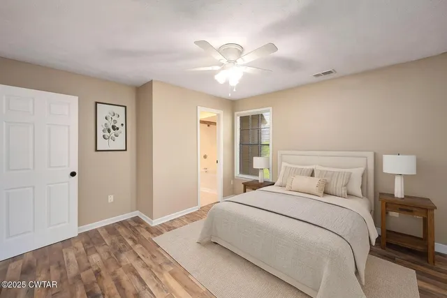 an empty room with wooden floor fan and windows